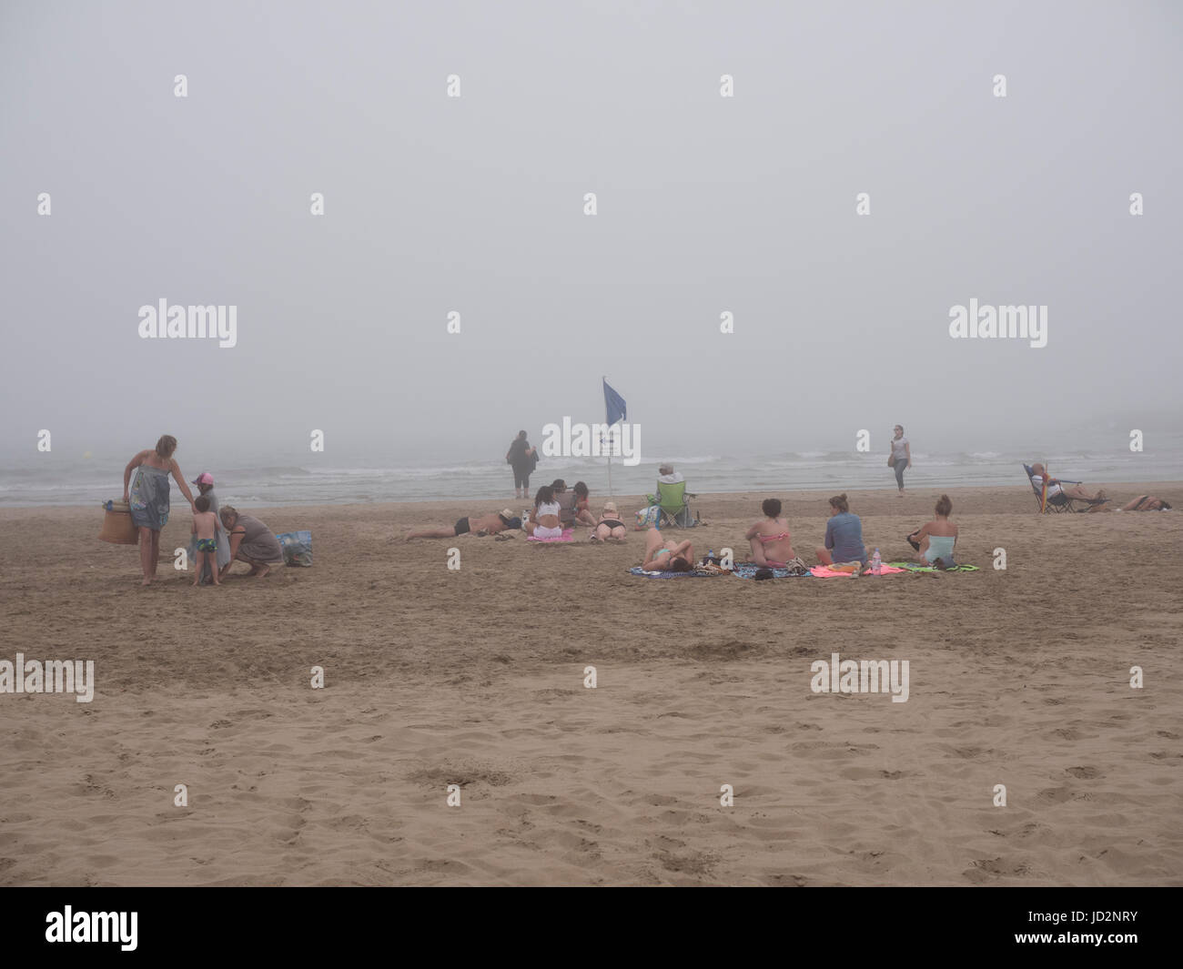 Sun bagnanti e famiglie lasciano una spiaggia in fretta come un freddo mare di nebbia in rotoli. Foto Stock