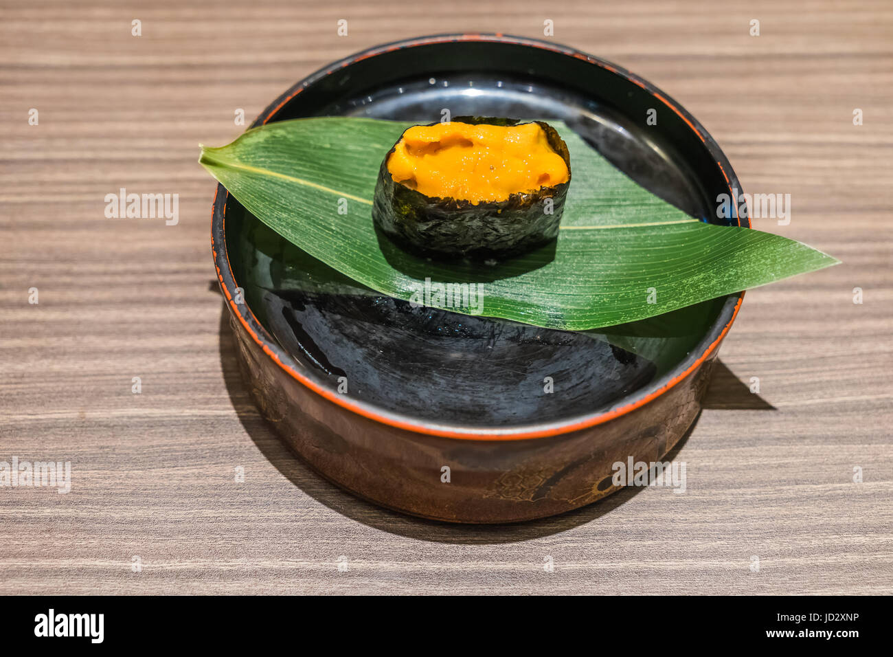 Uni Sushi Il cibo giapponese in lamiera nera e foglia sul tavolo di legno, ricci di mare Foto Stock