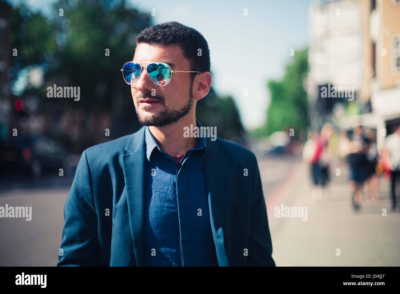 Un uomo che indossa gli occhiali da sole e una tuta sorgeva sulla strada. Foto Stock