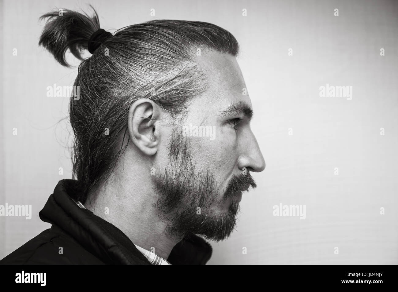 Profilo bianco e nero ritratto di profilo del giovane barbuto uomo asiatico al di sopra di grigio chiaro sfondo a parete Foto Stock