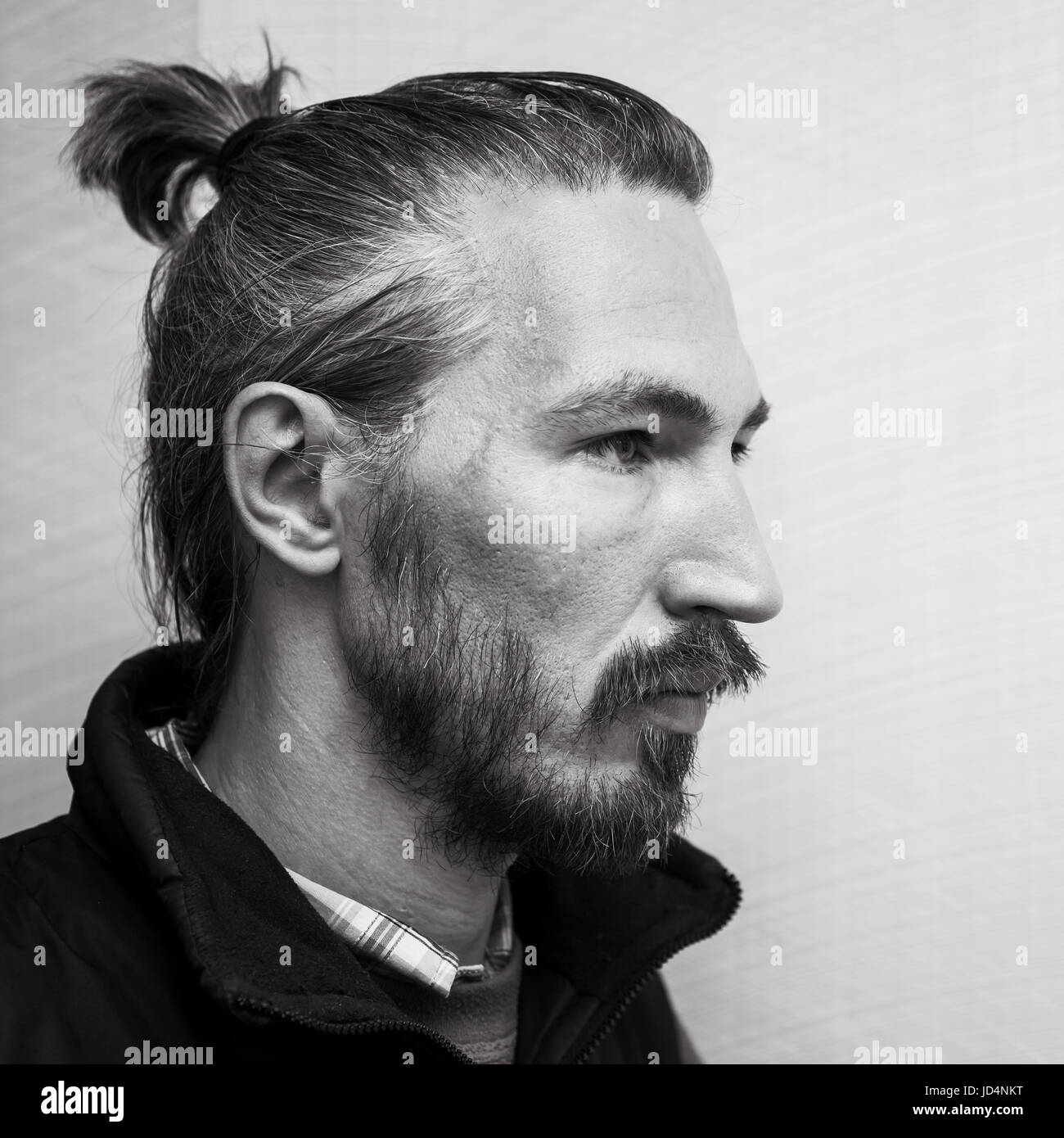 Profilo bianco e nero ritratto di Giovane barbuto uomo asiatico al di sopra di grigio chiaro sfondo a parete Foto Stock