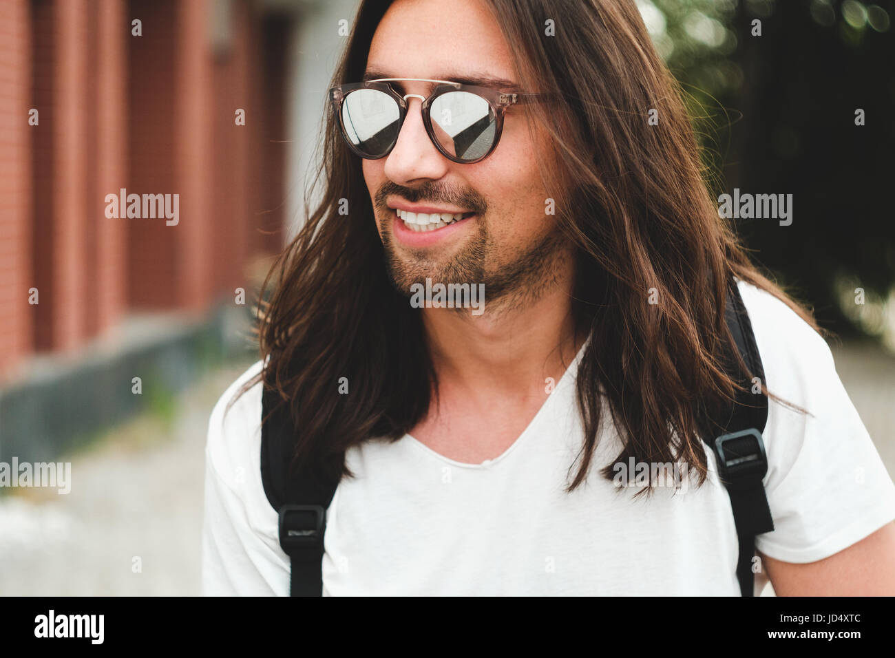 Tanga elegante modello con capelli lunghi stile di vita in strada. Vestito con una T-shirt bianco e strappato jeans blu nella città Foto Stock