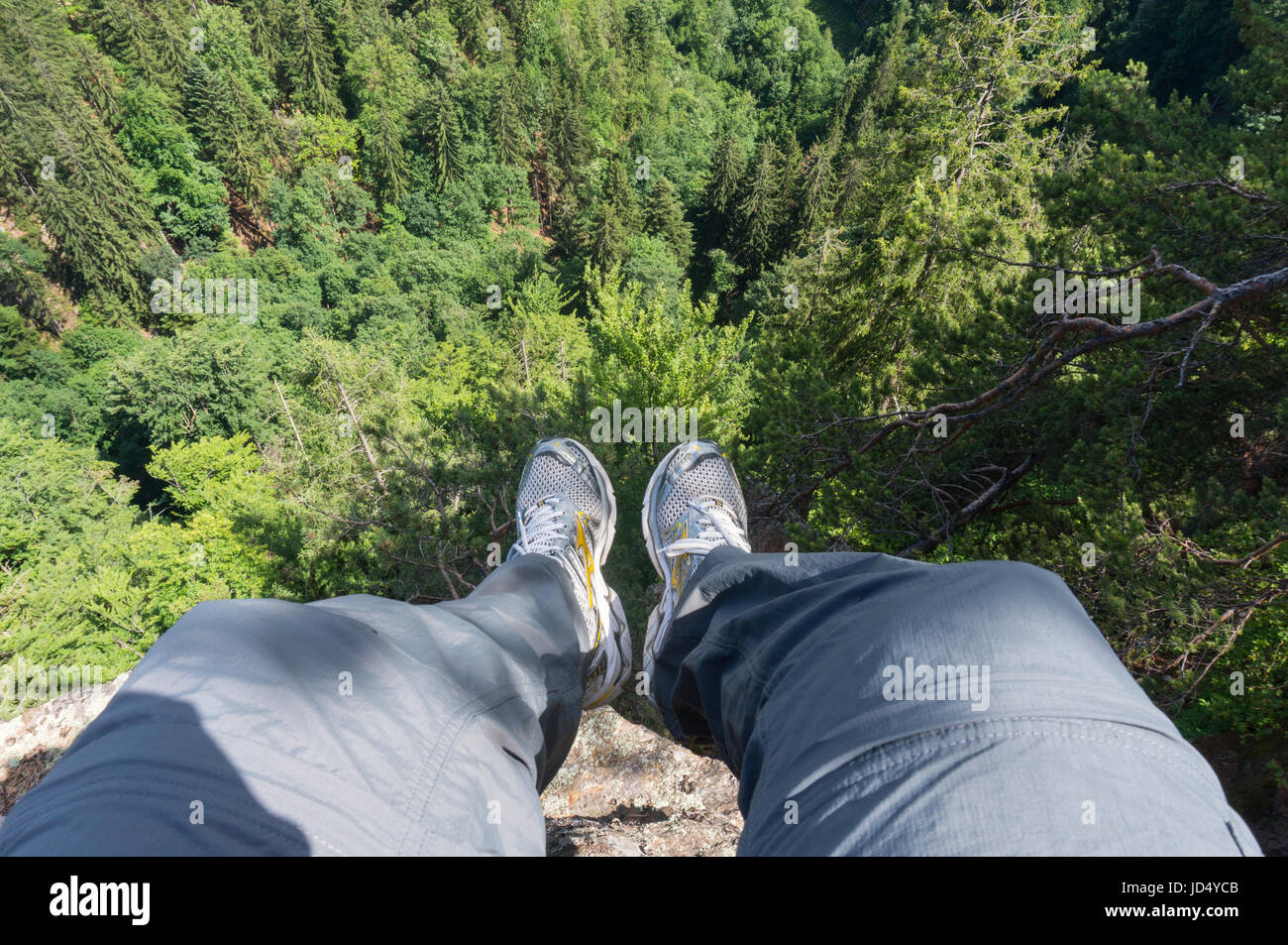 Le gambe oltre la scogliera del bordo Foto Stock