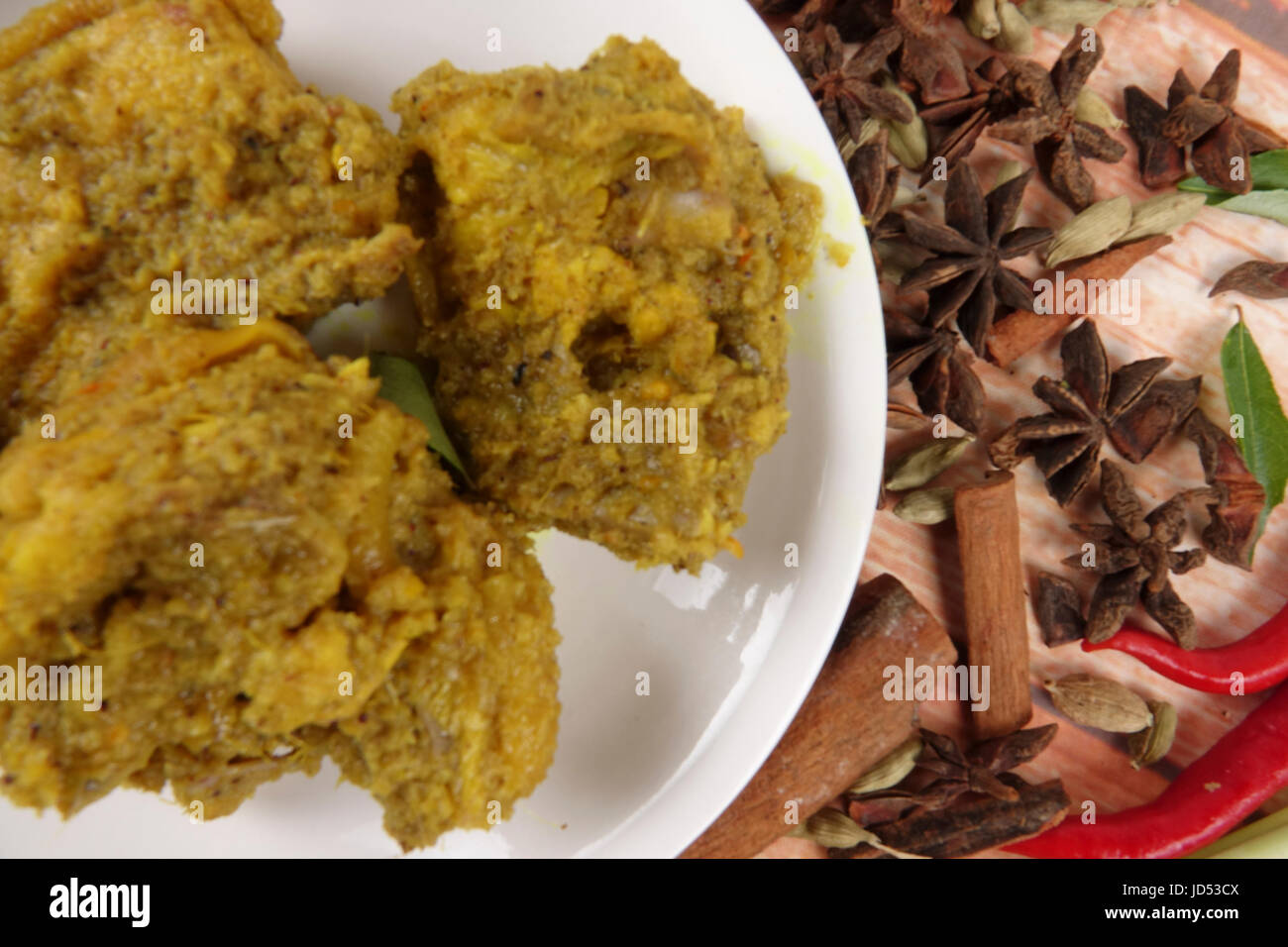 Piatto malese Rendang Ayam o a secco di pollo al curry e Ketupat Nasi (gnocco di riso) su sfondo di legno Foto Stock