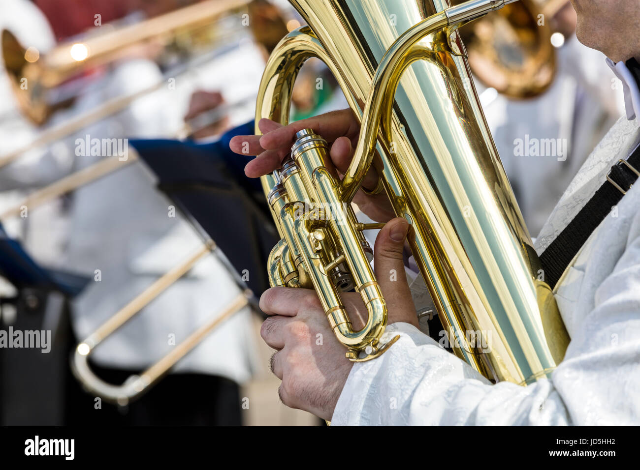 Le mani di un musicista maschio azienda big tuba sulla orchestra sfocata sullo sfondo Foto Stock