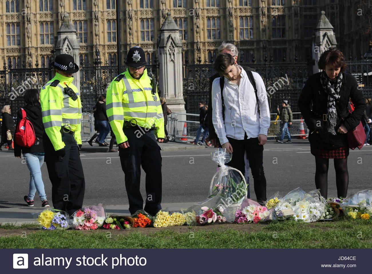Gli agenti di polizia e membri del pubblico visualizza fiori enunciati nella memoria del PC Keith Palmer e le altre vittime del terrore di Londra attacco. Foto Stock