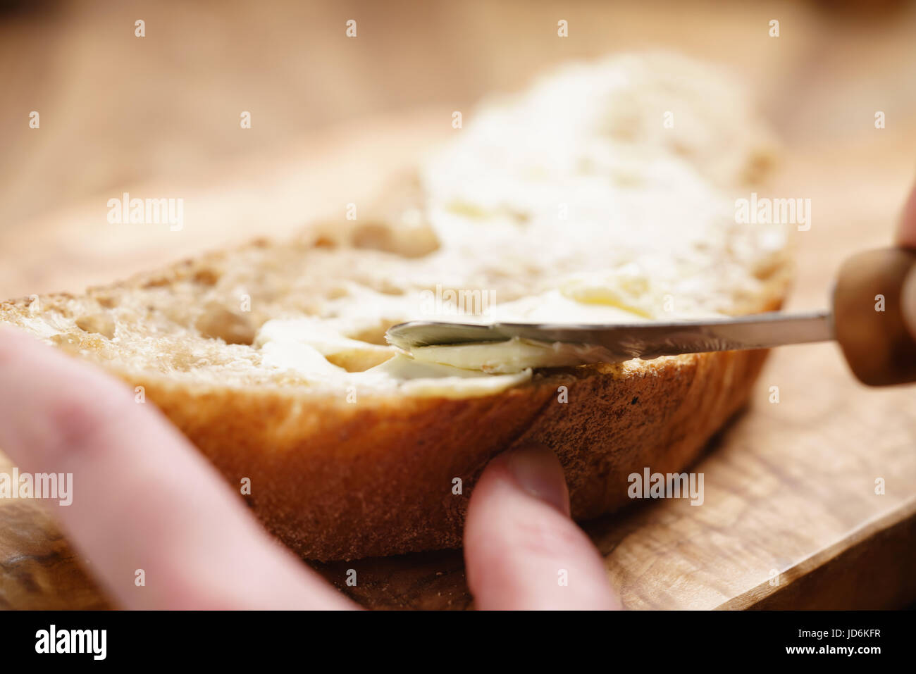 Giovani mani femminili diffusione di burro sul pane Foto Stock