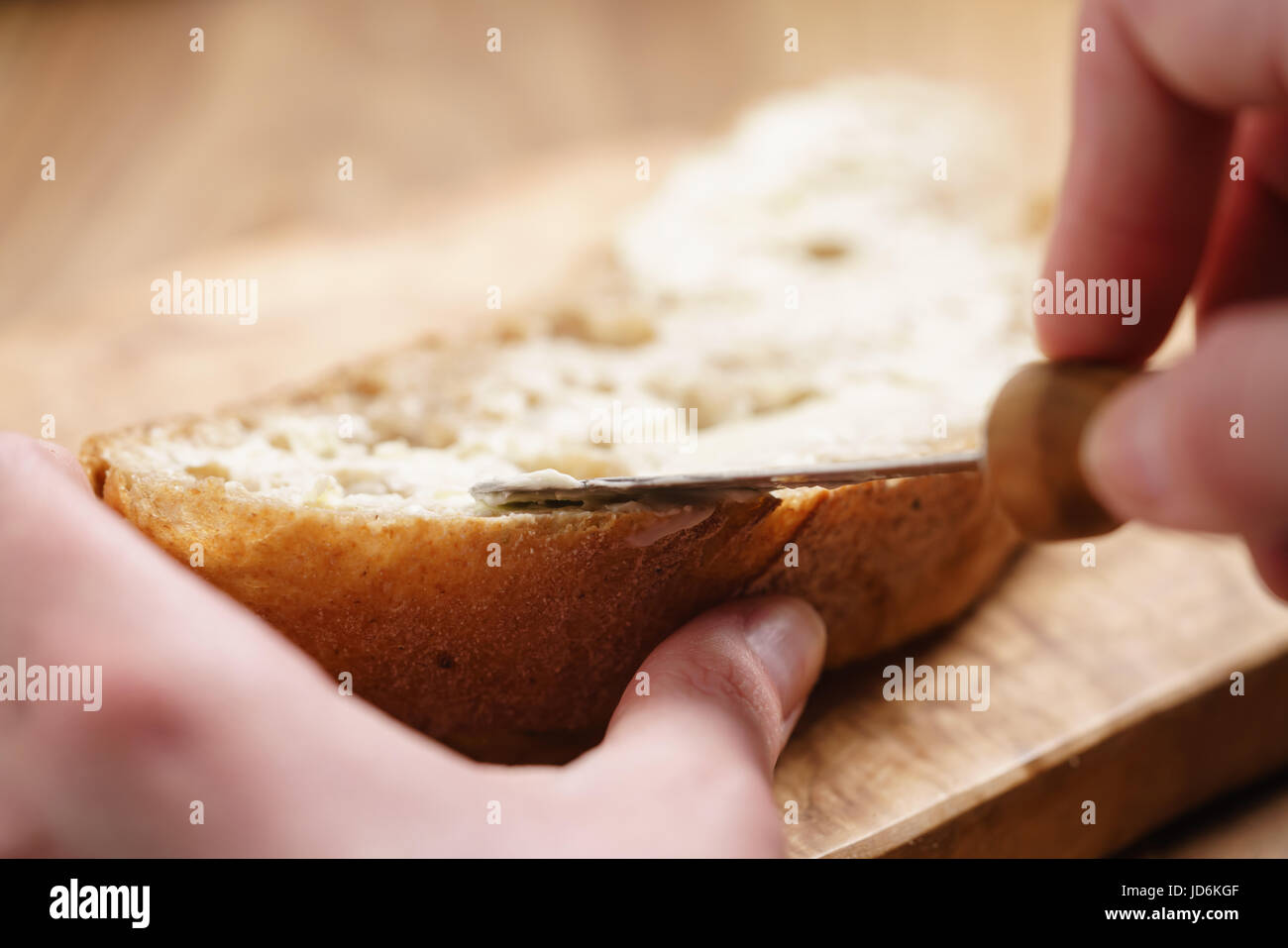 Giovani mani femminili diffusione di burro sul pane Foto Stock