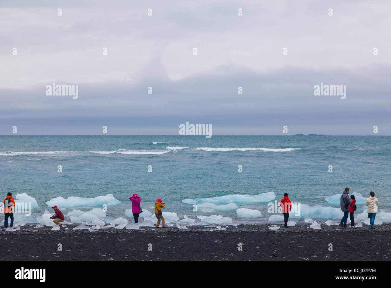 I turisti guardando i pezzi di ghiaccio galleggiante di Jokulsarlon laguna glaciale in Islanda Foto Stock