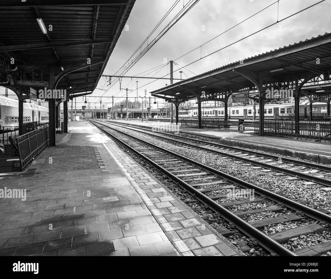 Vuota stazione ferroviaria piattaforma con binari del treno in bianco e nero, Belgio. foto a colori del trasporto in treno Foto Stock