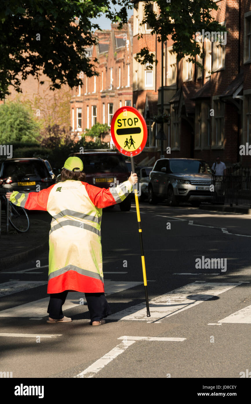Un lecca-lecca lady fermando il traffico su una strada di Londra Foto Stock