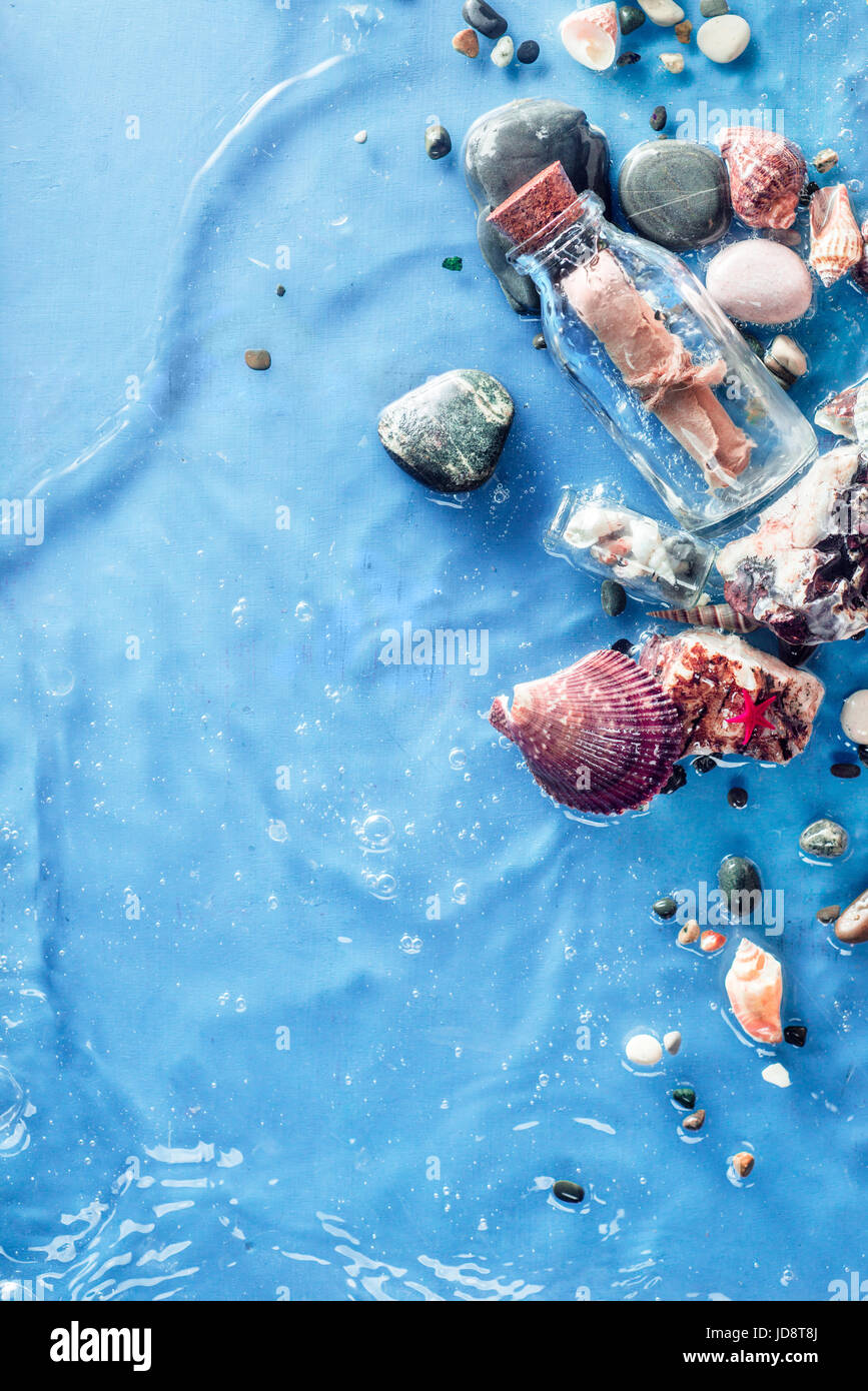 Copia marine space frame con un messaggio in bottiglia, conchiglie, ciottoli, sabbia e un ripple di seawave. underwater ancora in vita. Foto Stock