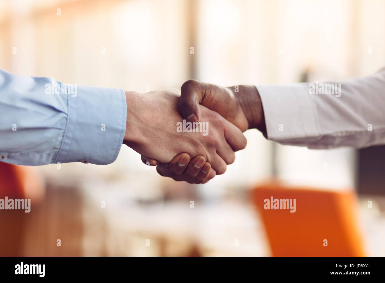 Stretta di mano tra africani e di un uomo caucasico Foto Stock