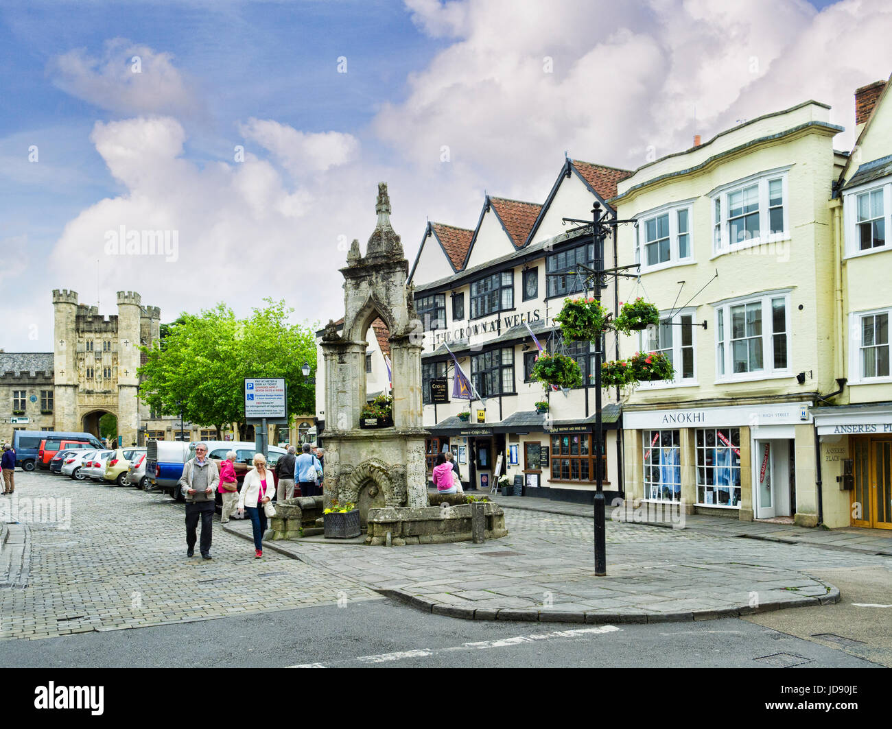 8 Giugno 2017: Wells, Somerset, Inghilterra, Regno Unito - Il centro storico della vecchia cattedrale della città di pozzetti, con la croce di mercato, Pay e Display parcheggio, pub, Foto Stock