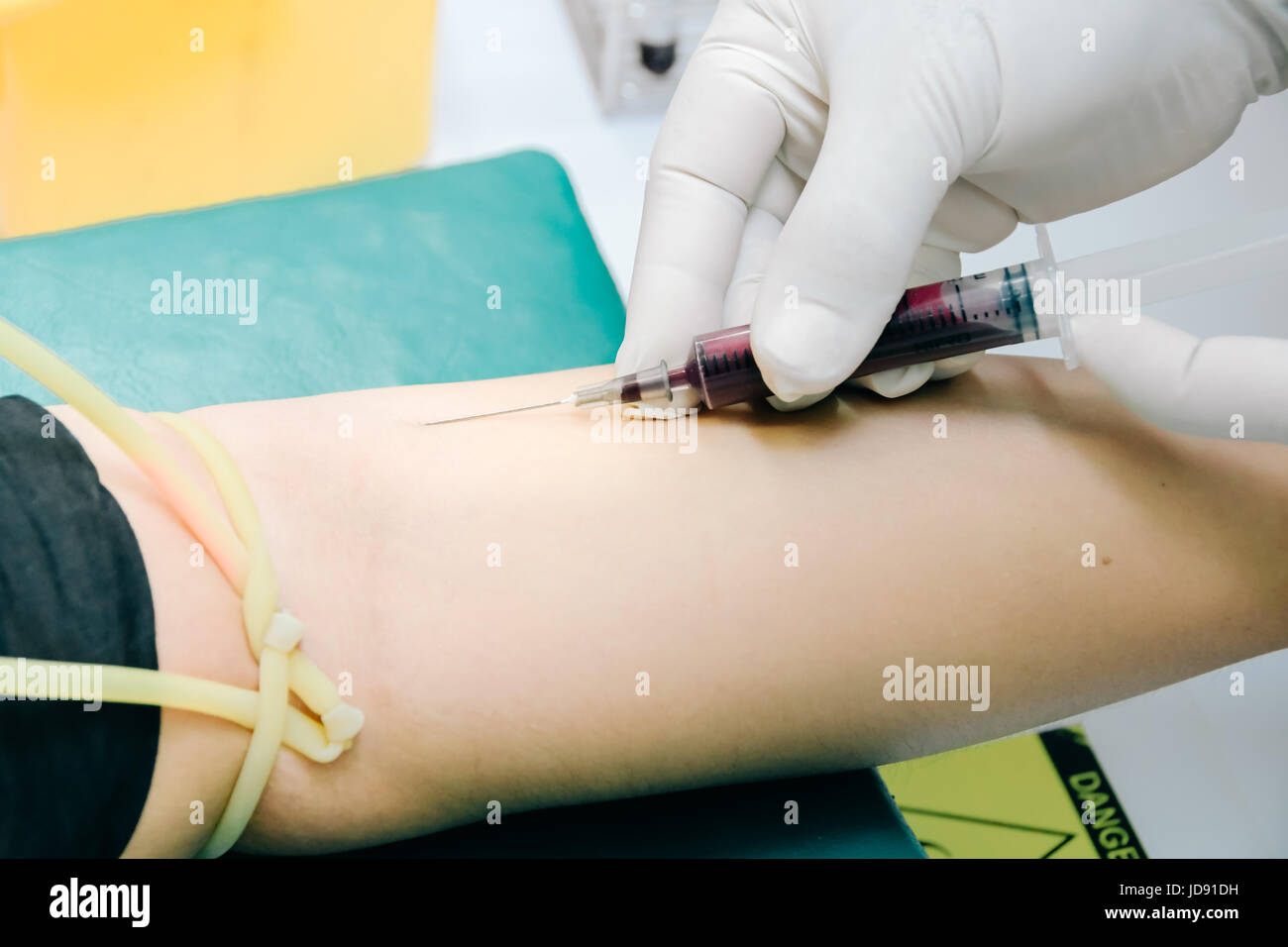 Medico o infermiere le mani in medical guanti blu mediante siringa con ago disegno campione di sangue dal braccio del paziente in ospedale. Scienziato get di prelievo del sangue per emodinamica Foto Stock