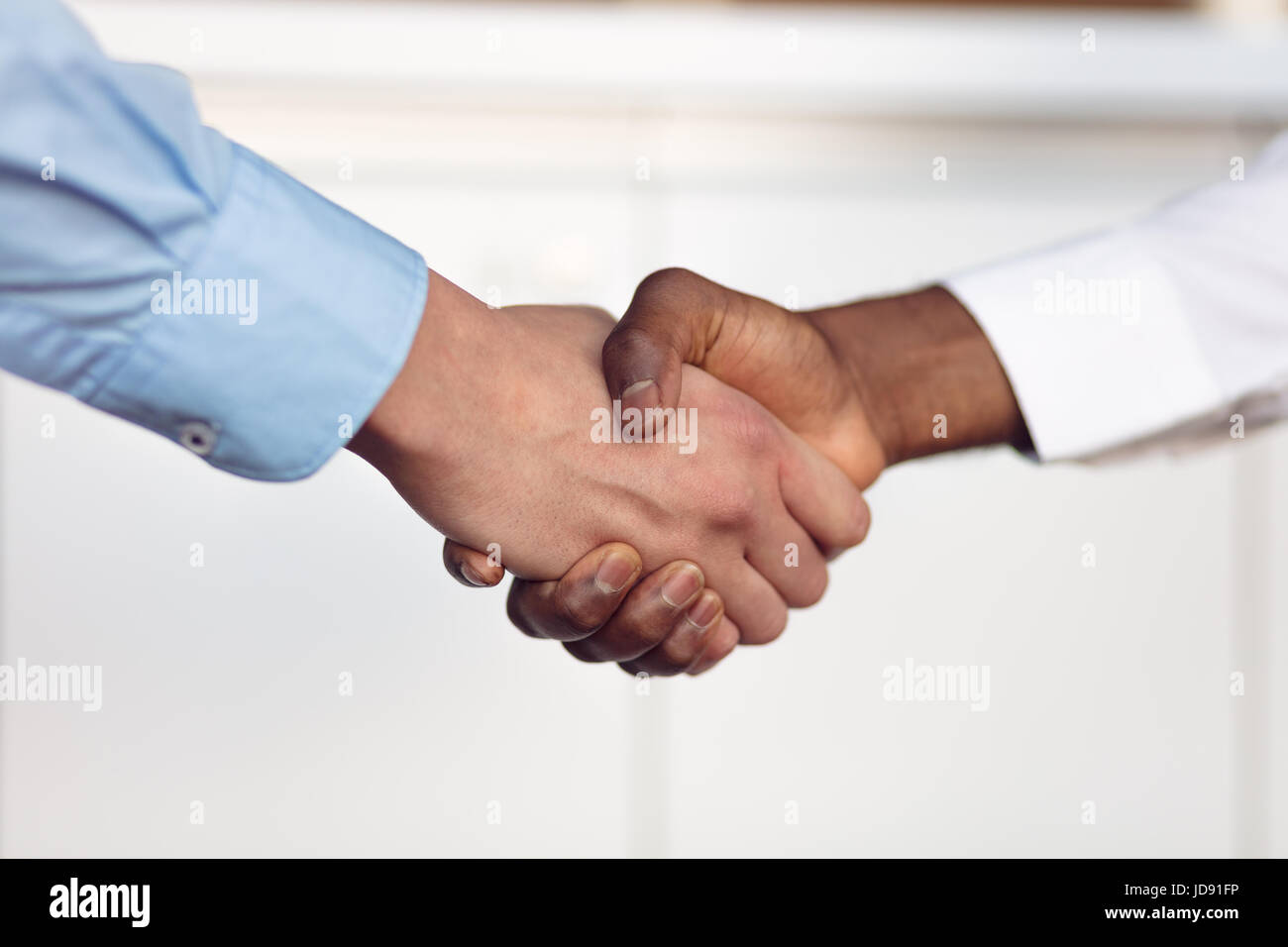 Stretta di mano tra africani e di un uomo caucasico Foto Stock