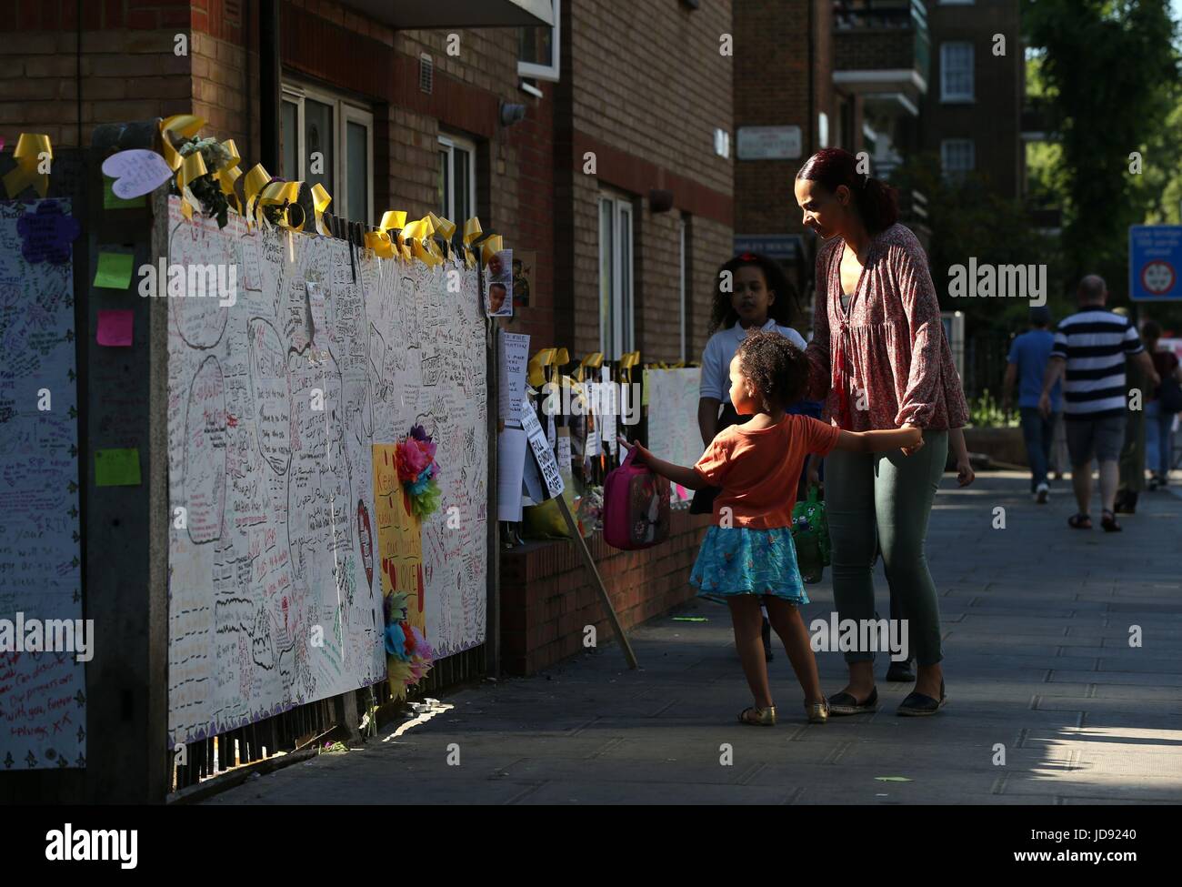Una madre e figlia pausa per guardare una parete di ricordo in corrispondenza della giunzione di Silchester Road e Bramley Road a ovest di Londra, vicino alla Torre di Grenfell dopo un incendio si propagò edificio a 24 piani sulla mattina di mercoledì. Foto Stock
