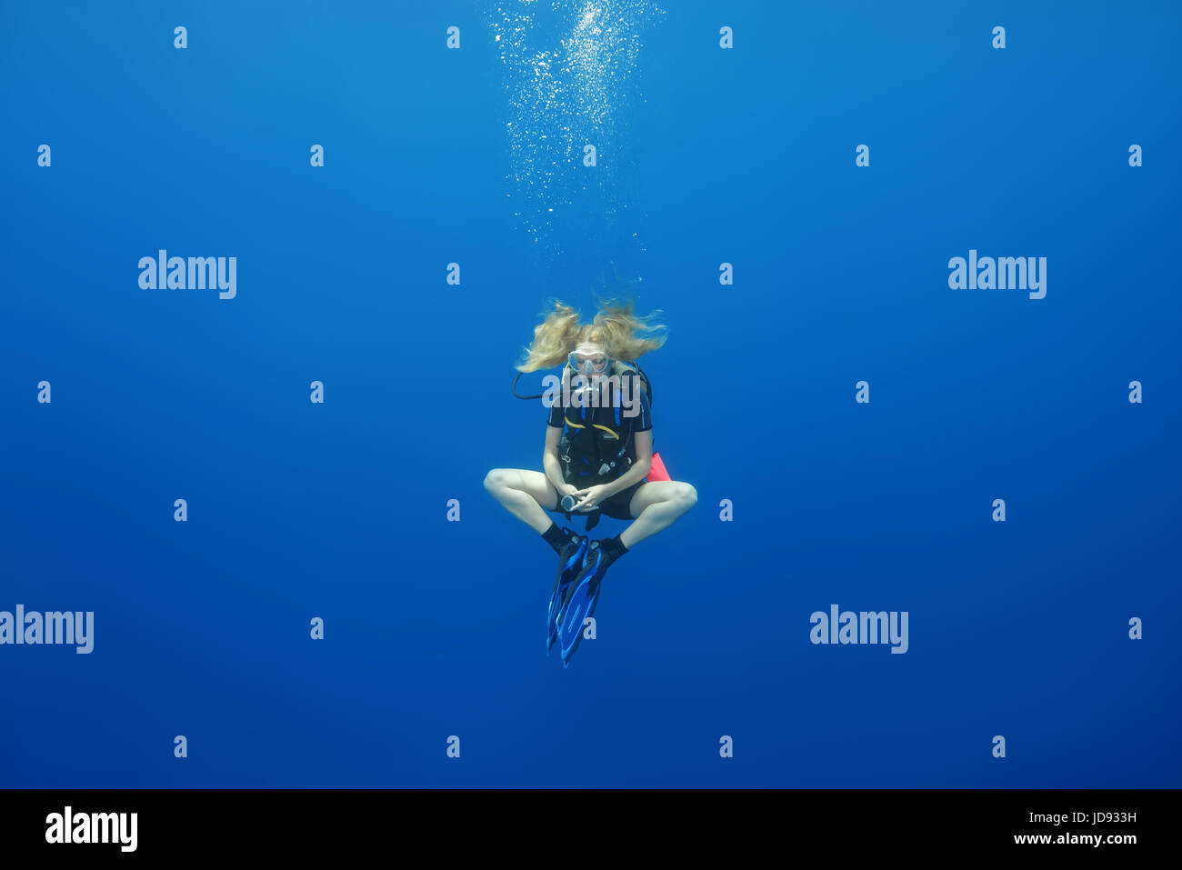 Femmina sub appeso in un loto posano per una sosta di sicurezza in acqua blu, Oceano Indiano, Maldive Foto Stock