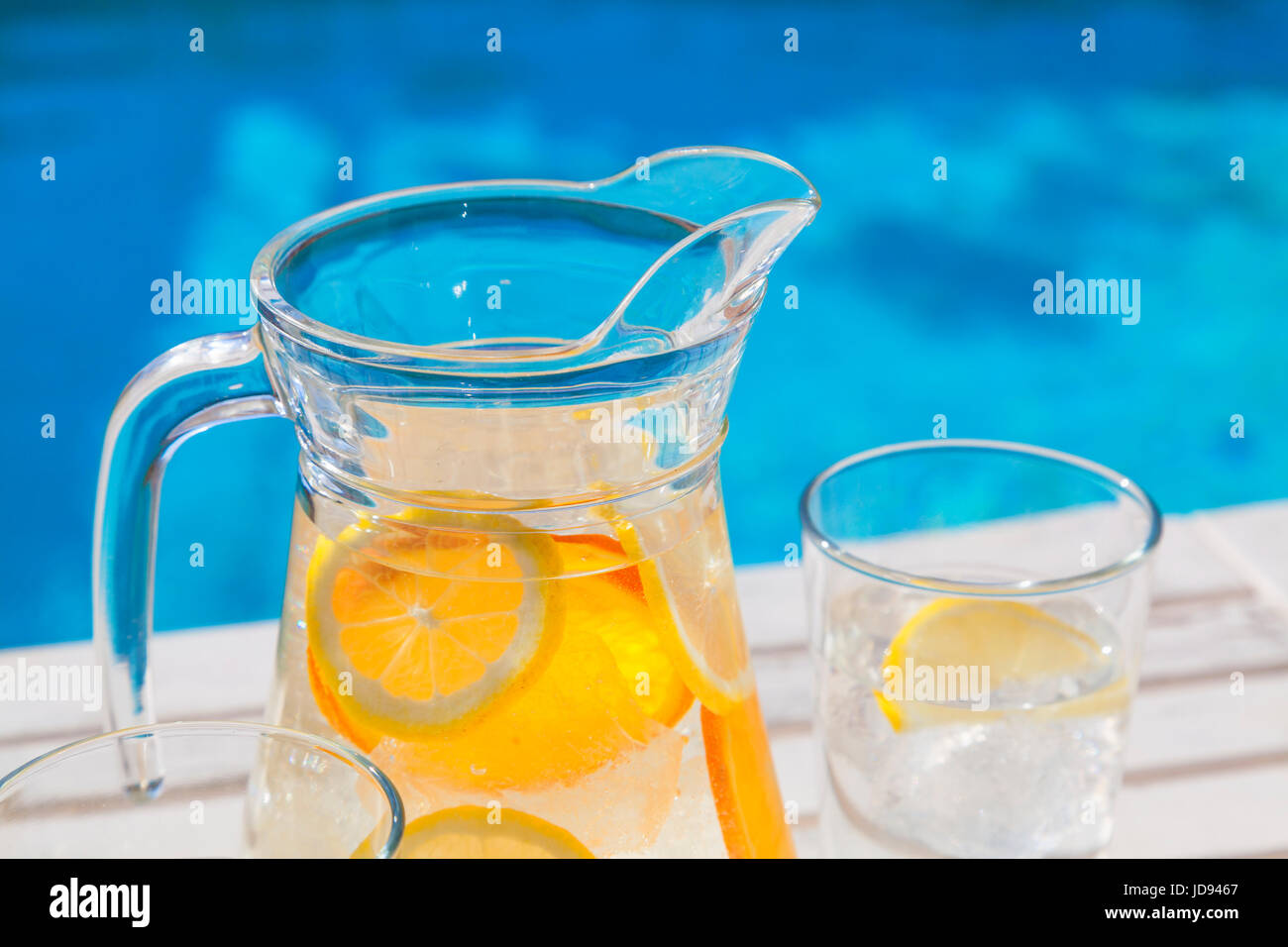 Un vaso di acqua ghiacciata con limone e arancio presso la piscina. Foto Stock