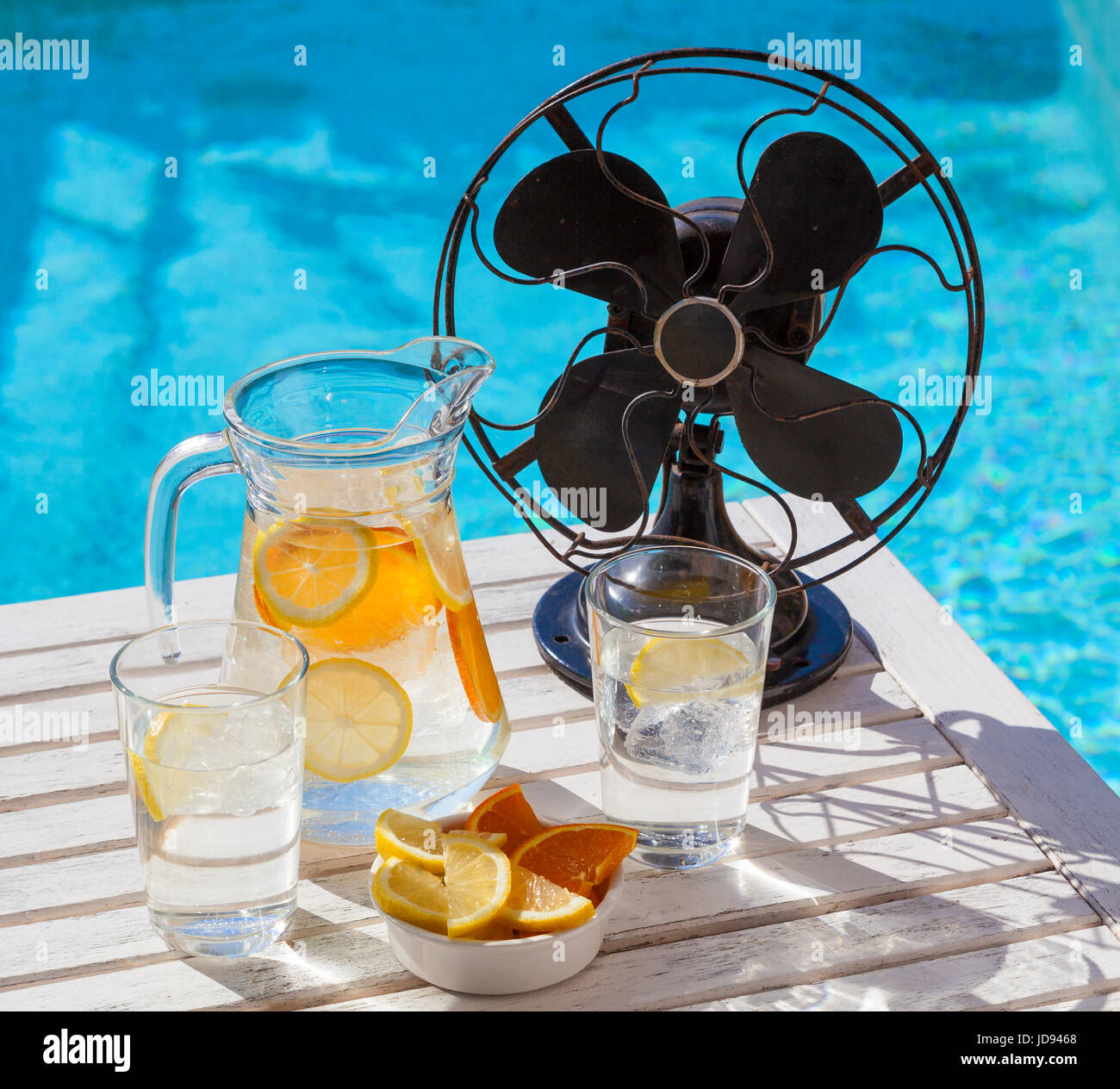 Le calde giornate estive durante una ondata di caldo. Un vaso di acqua rinfrescante e un ventilatore vintage presso la piscina. Foto Stock