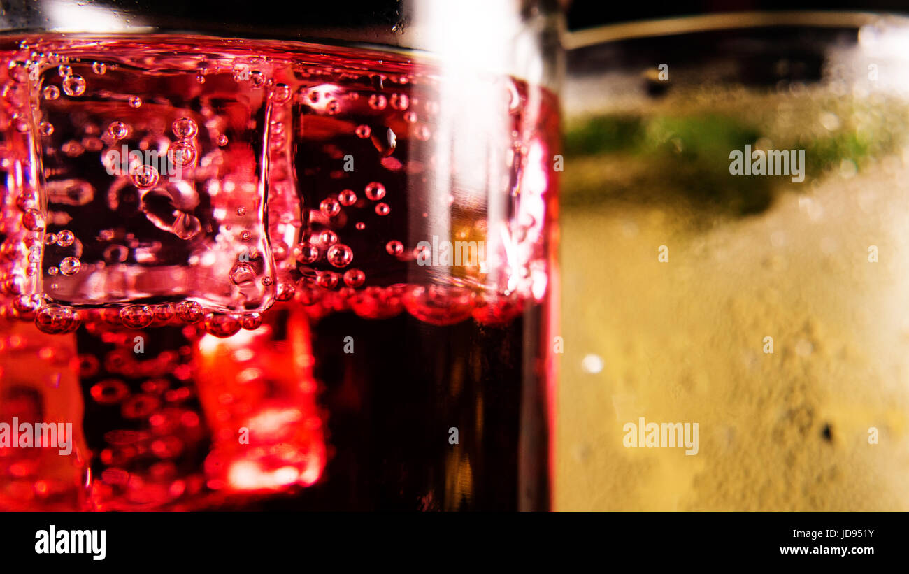 Le bolle di aria su cubetti di ghiaccio in un bicchiere con un drink rosso su sfondo anteriore closeup Foto Stock
