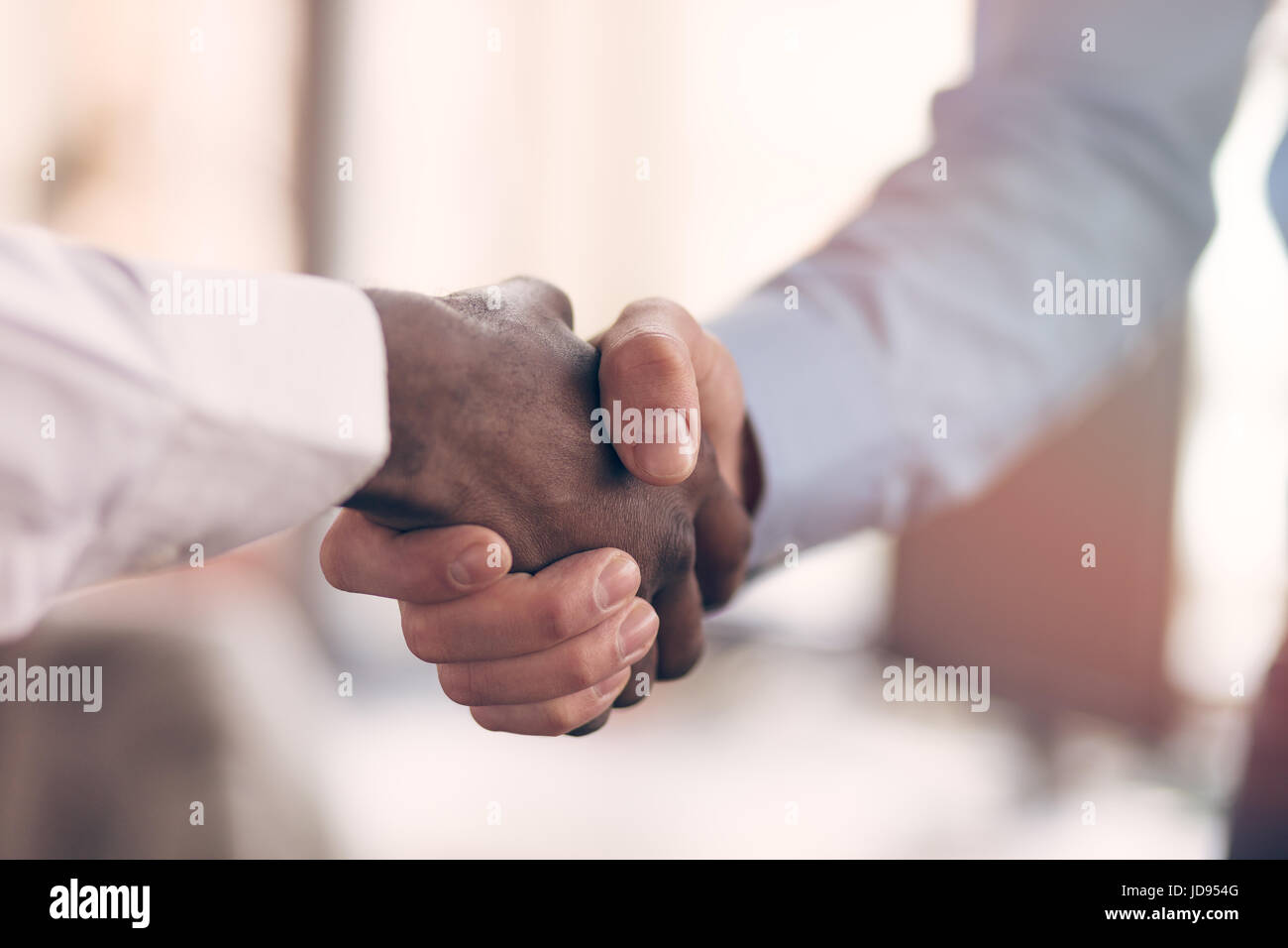Stretta di mano tra africani e di un uomo caucasico Foto Stock