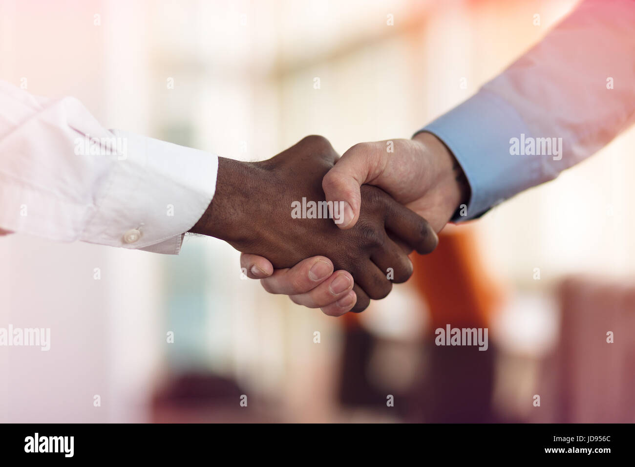 Stretta di mano tra africani e di un uomo caucasico Foto Stock