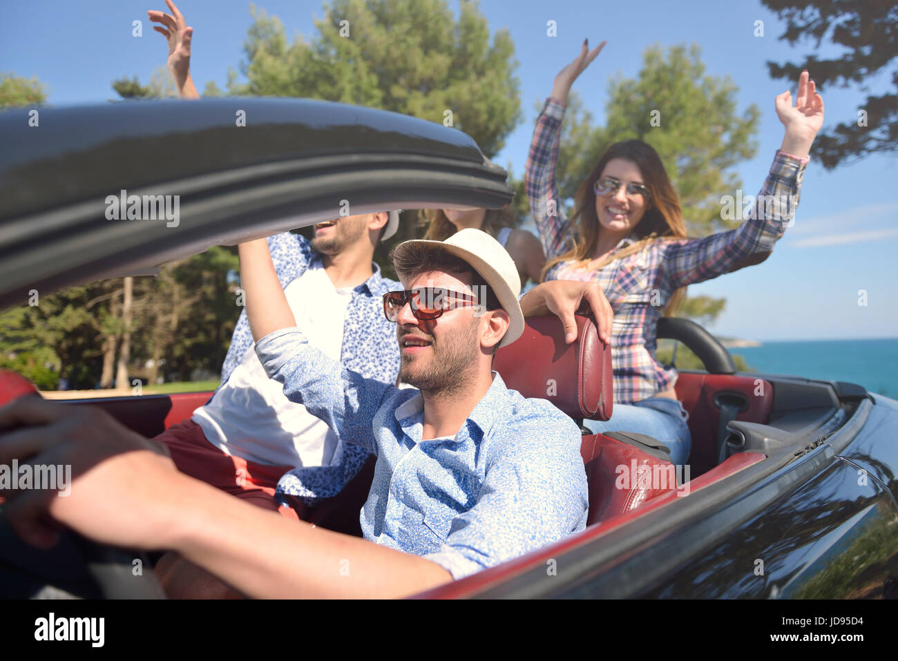 Tempo libero, viaggio, viaggiare e concetto di persone - happy amici guida  in cabriolet auto lungo la strada di campagna Foto stock - Alamy
