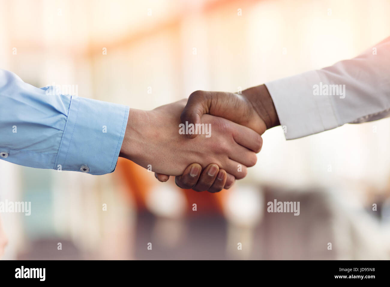 Stretta di mano tra africani e di un uomo caucasico Foto Stock
