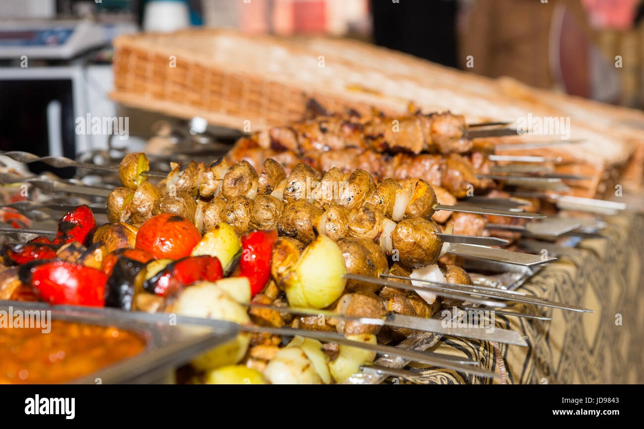 Bounty di carni cotte e verdure disposte ordinatamente su vassoi metallici al food festival Foto Stock