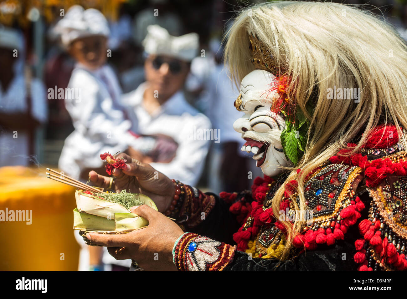 Strano e inquietante maschera indossata da un attore Balinese che utilizza le offerte di religiose di bruciare incenso e fiori come parte del divertimento di Bali Foto Stock