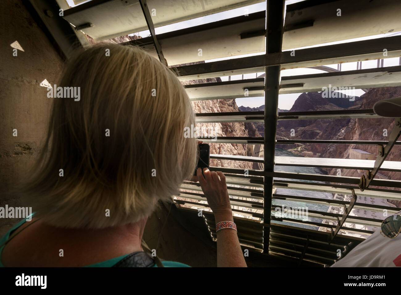 Testa e spalle colpo di donna fotografare vista attraverso le persiane della Diga di Hoover, Stati Uniti d'America. Foto Stock