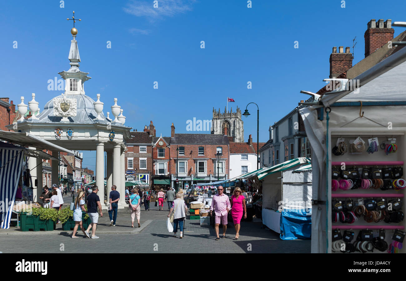 Shoppers godetevi il popolare mercato del sabato con la vista del palco per spettacoli e Chiesa di Santa Maria in una mattina di sole a Beverley, nello Yorkshire, Regno Unito. Foto Stock