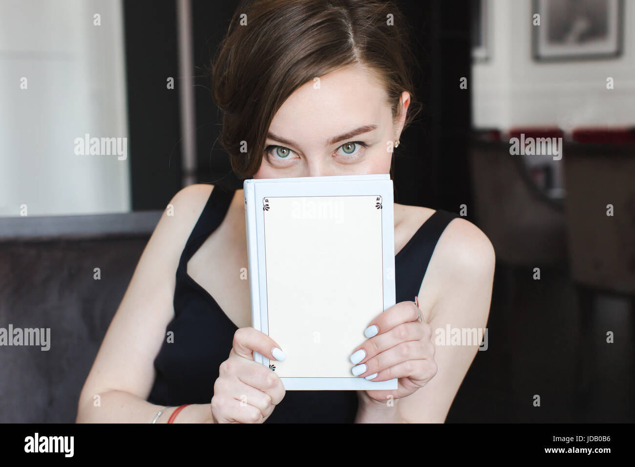 Donna che ricopre la faccia con libro Foto Stock