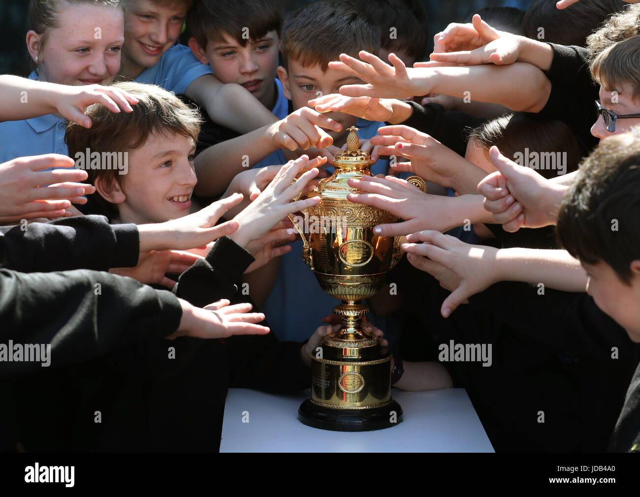 Sette principale allievo di Leo Fox(L)a fianco di compagni di classe tenta di mettere le mani sul trofeo di Wimbledon ha vinto da Andy Murray per una seconda volta lo scorso anno, sul display a Murrays ex scuola primaria a Dunblane in Scozia. Foto Stock