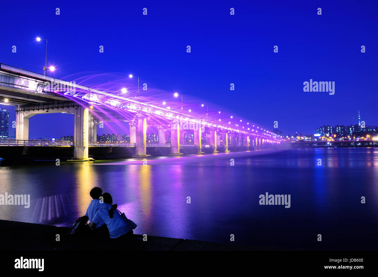Giovane amore seduti al ponte di banpo cercando arcobaleno spettacolo fontana di notte a Seoul, Corea Soth. Foto Stock