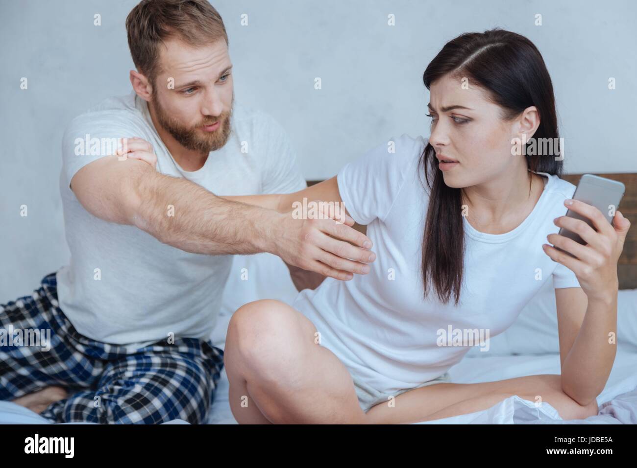 Giovani insoddisfatti brunette litigare con il mio ragazzo su smartphone Foto Stock