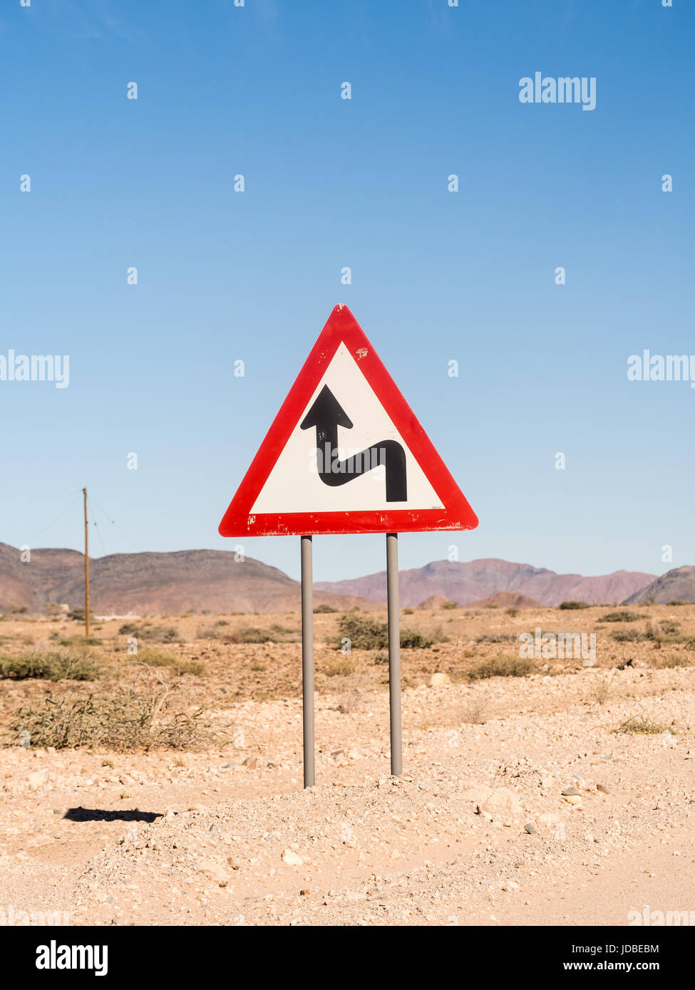 Segnale di avvertimento curve strette sulla strada di solitario sul deserto del Namib, Namibia, Africa. Foto Stock