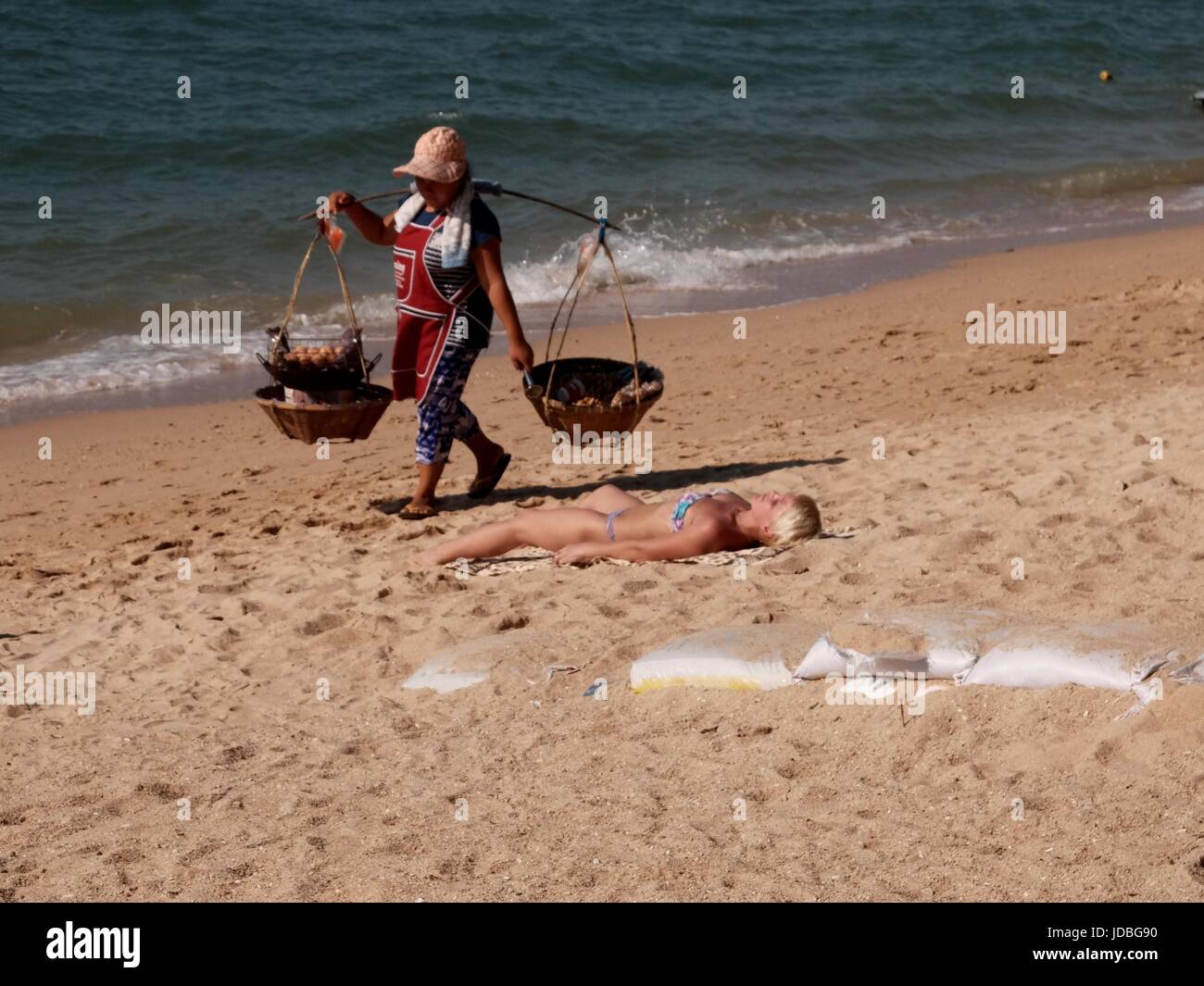 Cestello caring fornitore di prodotti alimentari a camminare sulla spiaggia di sabbia in Pattaya Thailandia Foto Stock