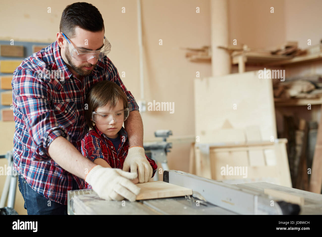 Giovane uomo e ragazzo lavorazione pezzo di legno sulla macchina di piallatura Foto Stock
