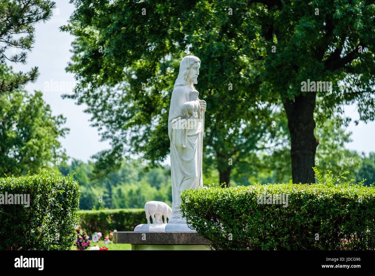 Una statua di Gesù Cristo con gli agnelli montato in un cimitero di Wichita, Kansas, Stati Uniti d'America su una mattina di primavera. Foto Stock