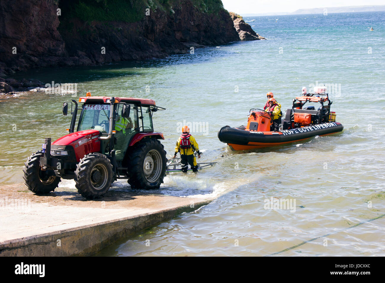 Scialuppa di salvataggio e dei battelli di salvataggio equipaggio a Hope Cove, Devon England. La scialuppa di salvataggio viene recuperato sul suo trattore e rimorchio dopo un viaggio per mare. Foto Stock