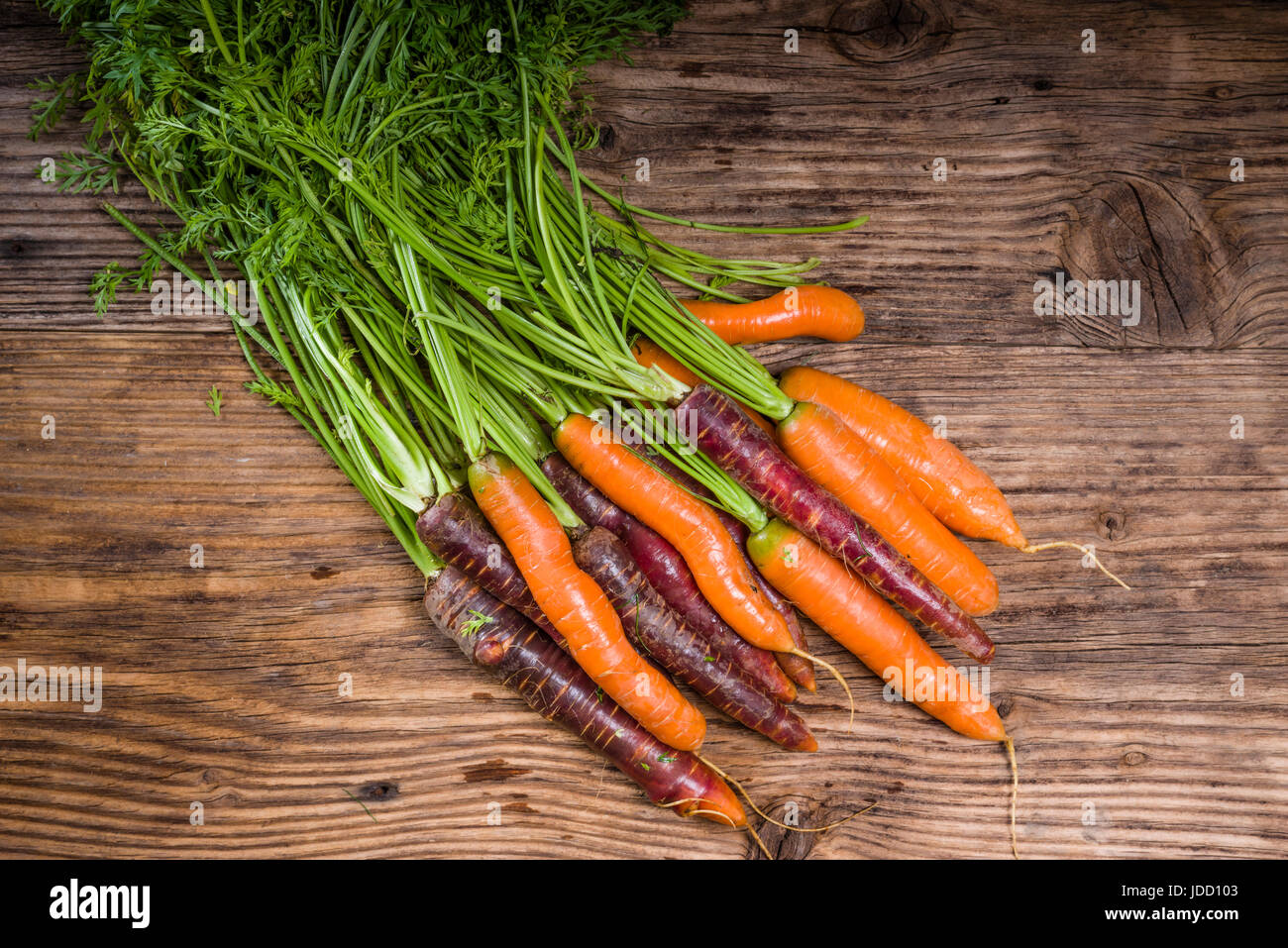 Mazzetto di colorate le carote fresche su una tavola in legno rustico Foto Stock