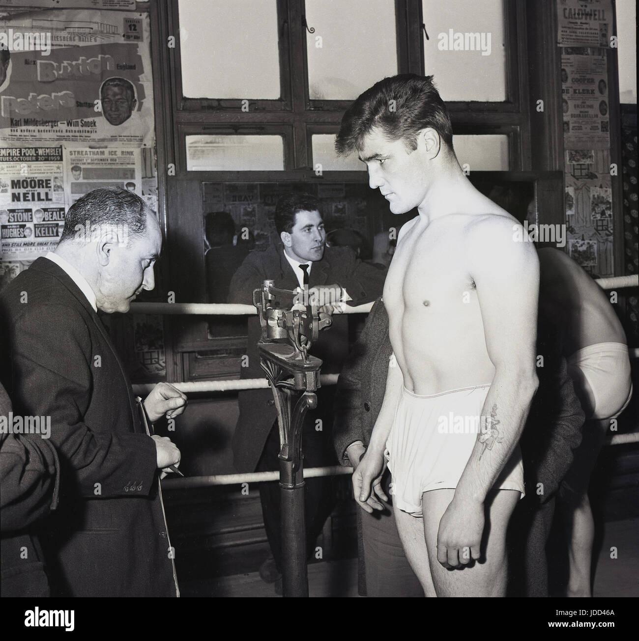 1959, all'interno della palestra del famoso pub Thomas A Beckett sulla Old Kent Road, Bermondsey, South London, SE1, Inghilterra, l'immagine mostra un pugile in piedi su un anello che viene ufficialmente pesato. Foto Stock 1959, all'interno della palestra del famoso pub Thomas A Beckett sulla Old Kent Road, Bermondsey, South London, SE1, Inghilterra, l'immagine mostra un pugile in piedi su un anello che viene ufficialmente pesato. Foto Stock