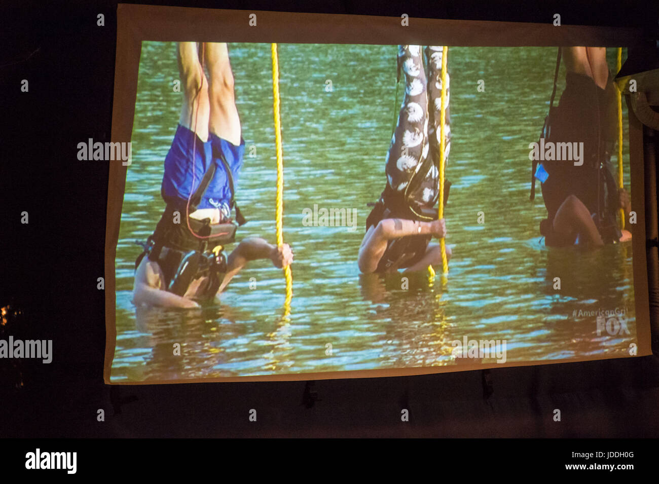 Merrick, New York, Stati Uniti d'America. 11 Giugno, 2017. Durante la graniglia americano Stagione 2 premiere, a sinistra in blu costume da bagno, CHRIS EDOM, 48, di Merrick, appeso a testa in giù con la sua testa sott'acqua come lui e gli altri concorrenti sono abbassati nel lago durante una sfida. Spettacolo è stato proiettato su grande schermo durante Edom's backyard partito di osservazione per l'episodio 1 della rete di FOX realtà serie televisiva. Edom è stato da ultimo di 16 concorrenti prelevati per un team che l'episodio. Credito: Ann Parry/ZUMA filo/Alamy Live News Foto Stock