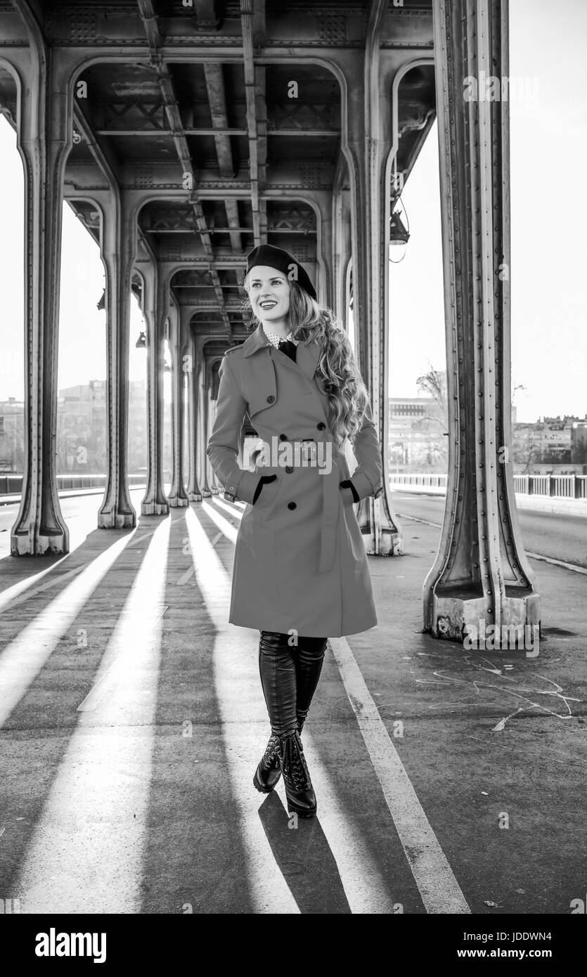 Luminose a Parigi. A piena lunghezza Ritratto di felice giovane turista woman in red trench coat sul Pont de Bir-Hakeim bridge in Paris guardando in lontananza Foto Stock