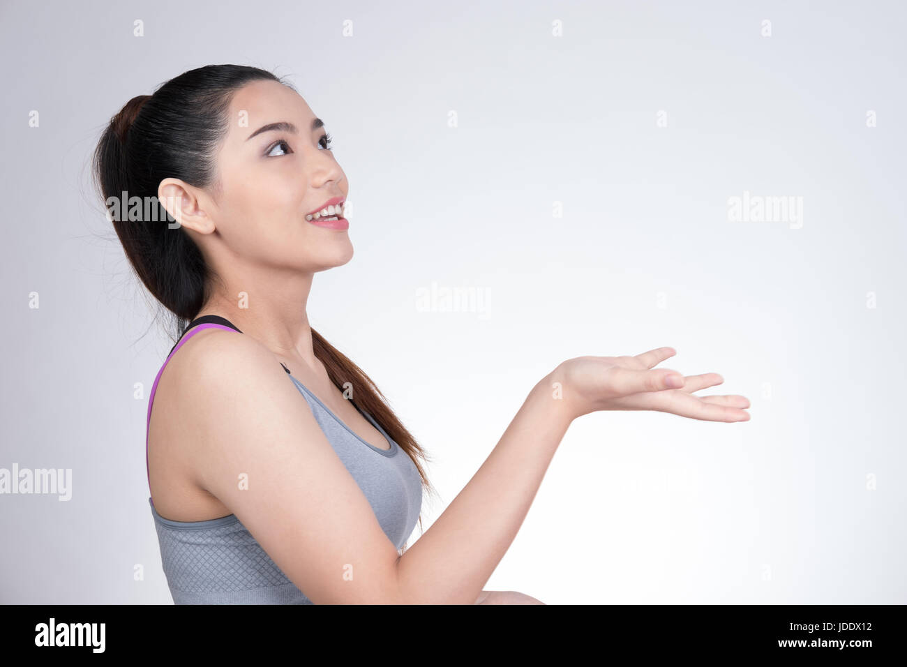 Giovani sani asiatici sportivo atletica Ragazza donna in grigio top lanci qualcosa in aria con studio shot sfondo bianco Foto Stock