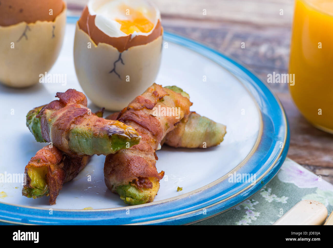 Uova sode con pancetta avocado soldati sul tavolo in giardino Foto Stock