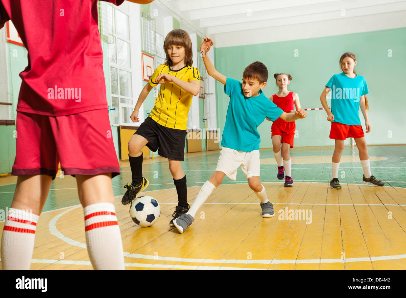 Ritratto di preteen ragazze e ragazzi che giocano a calcio in palestra della scuola Foto Stock