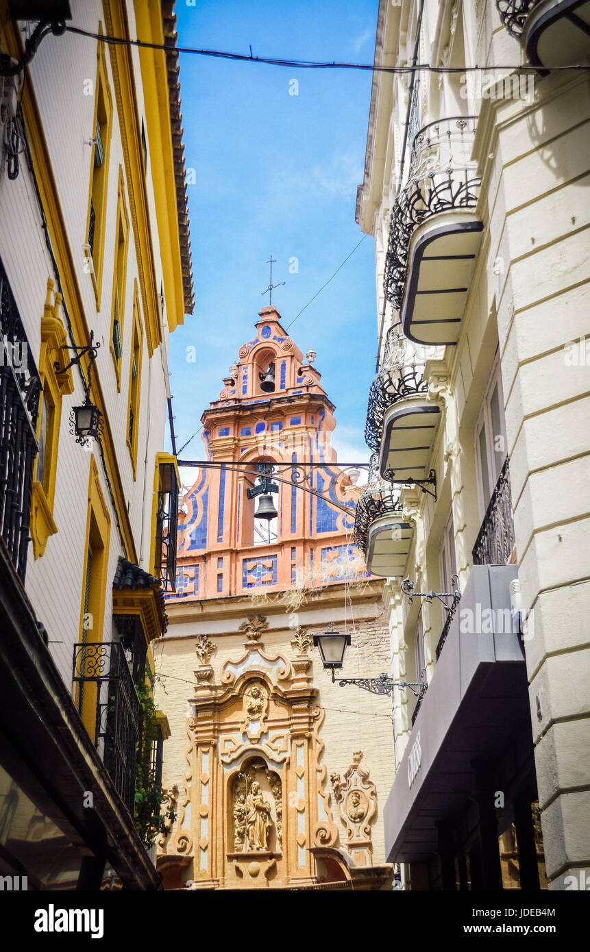 Strada stretta a Siviglia con una bella chiesa Foto Stock